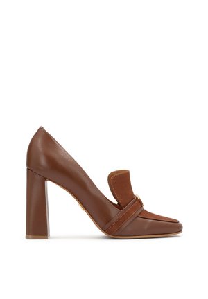 Brown leather high-heeled shoe with a pointed toe, square strap detail, and a thick block heel. Smooth texture and minimalist design.