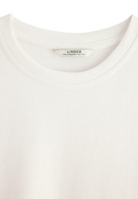 Hvid bomulds t-shirt med rund halsudskæring. Har en glat tekstur og søm detaljer. Mærkeetiket synlig indeni kraven.