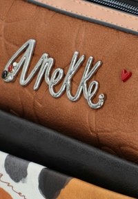 Braune strukturierte Kunstledertasche mit silbernem Markenlogo, rotem Herzakzent und darunterliegenden schwarzen sowie gemusterten Schichten.