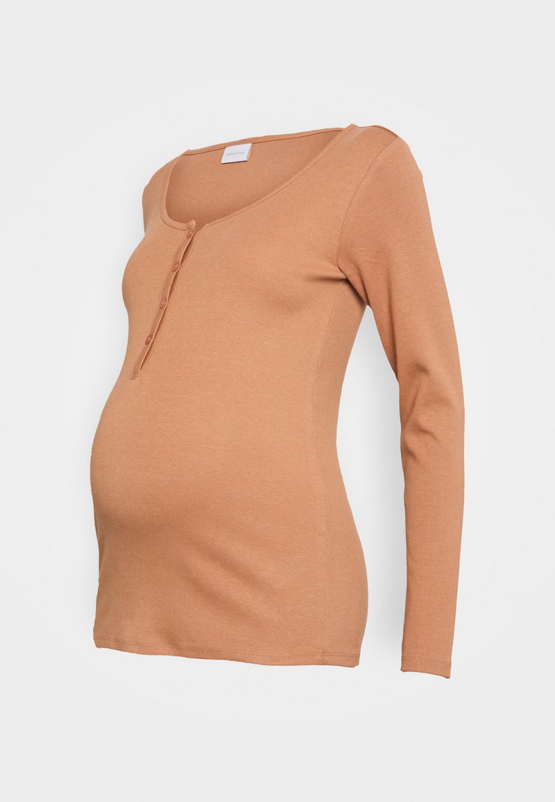 Blusa de maternidade de manga longa, na cor ferrugem, feita de um tecido suave, com decote em V e três botões na parte da frente. Design liso e ajustado.