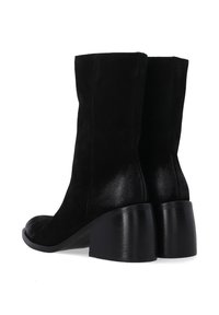 Schwarze Wildleder-Ankle Boots mit einer strukturierten Silhouette, abgerundeter Spitze und einem texturierten, glänzenden Absatz. Glatte Seitennähte sind sichtbar.