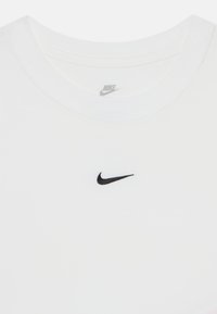 Fehér pamut póló fekete hímzett Nike logóval a mellkason középen. Kerek nyakú és rövid ujjú.