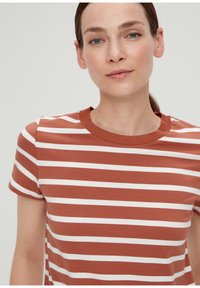 Gestreiftes T-Shirt in Rost und Weiß. Kurze Ärmel, Rundhalsausschnitt mit geripptem Struktur. Aus Baumwolle, taillierte Passform. Einfache, lässige Muster.