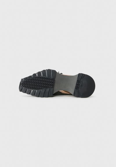 Schwarze Gummisohle eines Sneakers mit einem strukturierten Profil, das eine leichte Kurve an der Ferse und eine flache Vorderseite aufweist.