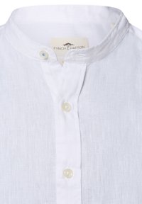 Witte linnen shirt met een bandkraag, voorzien van een knoopsluiting met drie knopen. Zachte textuur en lichtgewicht stof. Merkenlabel zichtbaar binnenin de kraag.