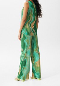 Conjunto de top sin mangas plisado en verde y beige con un estampado, y pantalones de pierna ancha, fabricado en material ligero. Presenta un diseño fluido y texturizado.
