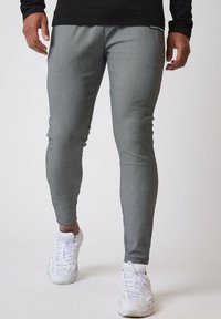 Grå atletiske leggings med en tekstureret overflade, tætsiddende design og elastisk talje, parret med hvide atletiske sko.