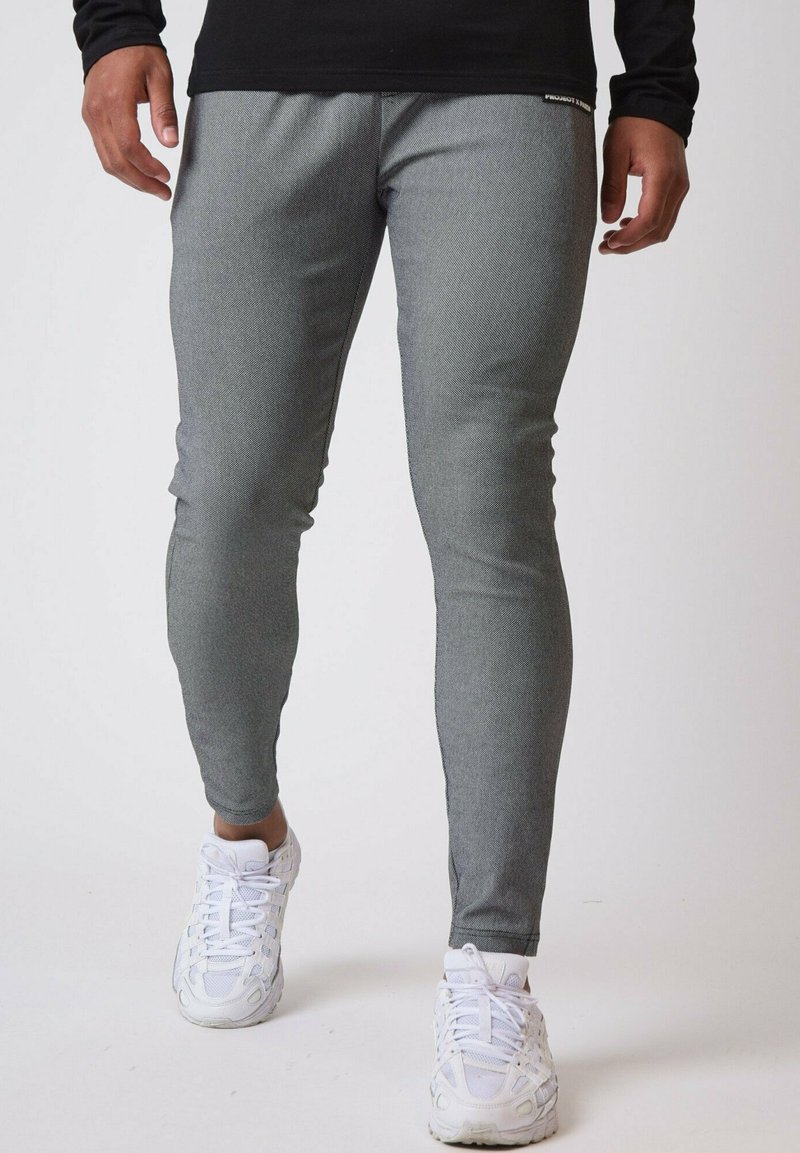 Grå atletiske leggings med en tekstureret overflade, tætsiddende design og elastisk talje, parret med hvide atletiske sko.