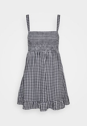 Sort og hvid ginghamsolkjole med smocket overdel, firkantet halsudskæring, tynde skulderstropper og flæsekant.