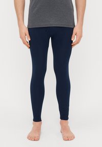 Ναυτικό μπλε κολάν φτιαγμένα από ελαστικό υλικό, σχεδιασμένα με εφαρμοστή γραμμή και αδιάσπαστη κατασκευή, φορεμένα με ένα γκρι t-shirt.