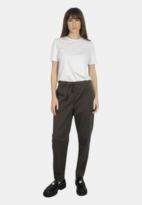 T-shirt bianca a maniche corte con collo rotondo abbinata a pantaloni larghi marroni scuri e scarpe platform nere. Design a taglio dritto con vita elastica.