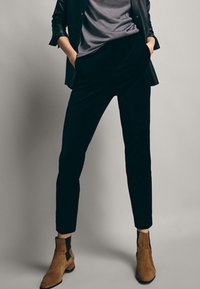 Svarta kordflöjts slim-fit byxor med en jämn textur. Matchas med bruna ankelstövlar med sidokut. Stylat med en grå T-shirt.