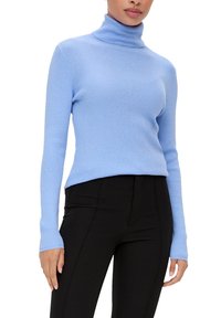Helles blauer, gerippter Rollkragenpullover mit langen Ärmeln und einer figurbetonten Passform. Kombiniert mit schwarzen, eng anliegenden Hosen.
