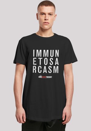 Svart bomullst-skjorte med stor hvit tekst som leser "IMMUNETOSARCASM" og en liten logo for "THE BIG BANG THEORY" nederst.
