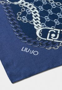 Sinine kangas valgete ahelate ja klambrite mustriga, brändi nimi "LIU·JO" trükituna valgena serva lähedale.