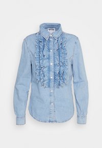 Ljusblå denimskjorta med volangdetalj framtill, spetsig krage och knäppning. Långa ärmar med knäppta manschetter.