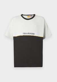 Κοντομάνικο μπλουζάκι με λευκό πάνω μέρος και μαύρο κάτω μέρος. Διαθέτει κίτρινη διακοσμητική γραμμή και το λογότυπο «BILLABONG» σε λευκό χρώμα.