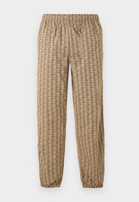 Pantaloni jogger beige con vita e caviglie elastiche, caratterizzati da un motivo geometrico ripetuto di forme stilizzate "B" marrone scuro.