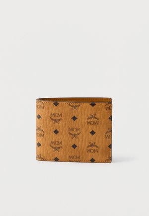 Cartera bi-fold de cuero marrón con logos negros de MCM y patrones de diamantes sobre un fondo blanco.