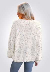 Chunky gebreide trui in roomkleur met multikleurige spikkels. Heeft een losse fit, een geribbelde rand en brede mouwen. Gelaagd uiterlijk.