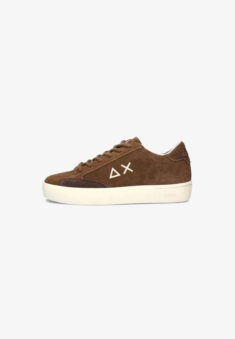 Sneaker in suede marrone con suola in gomma crema, punta tonda e logo geometrico sul lato. Texture liscia con dettagli di colori a contrasto.
