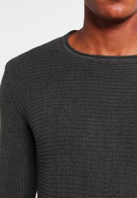 Dunkelgrauer strukturierter Pullover mit rundem Ausschnitt, der ein geripptes Strickmuster und eine weiche Oberfläche aufweist. Geeignet für die Freizeit.