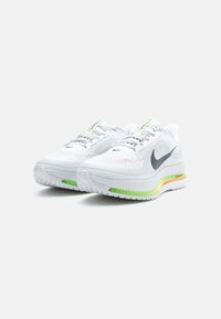 Λευκά αθλητικά παπούτσια με υφή πλέγματος στο πάνω μέρος, ασημένιες λεπτομέρειες, μεσαία σόλα σε πράσινο και πορτοκαλί χρώμα, και έντονο λογότυπο σούσο.