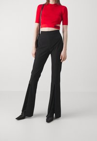 Top corto rojo con mangas cortas; pantalones negros de cintura alta con aberturas en el dobladillo; combinados con botines negros de punta; diseño minimalista.