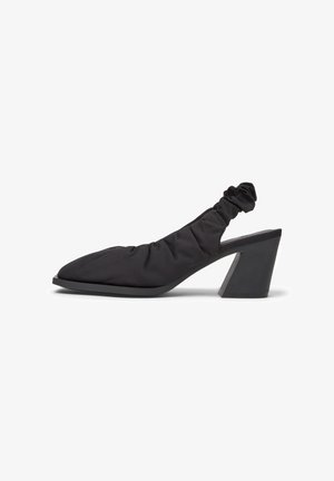 Zapato de tacón negro con tira en el talón y punta redondeada, con tejido fruncido y un tacón grueso que proporciona estabilidad y comodidad.