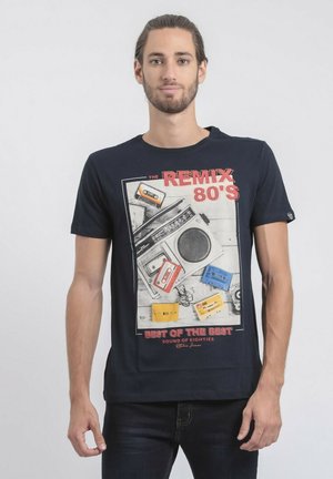 T-shirt noir avec un imprimé graphique vintage d'une cassette audio des années 80 et d'un boombox, avec des accents de couleurs vives et un col rond.