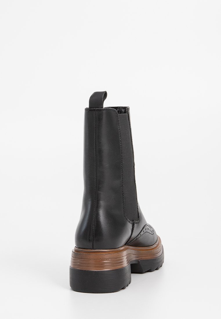 Stivaletti neri in pelle con pannelli elastici sui lati, punta arrotondata e bordo in pelle. Presentano un tacco spesso marrone e una linguetta per la presa.