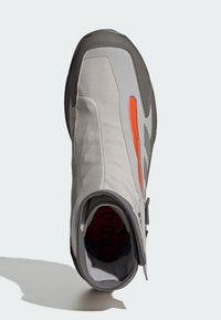 Grå tygsko med orange detalj, slimmad design, blixtlåsförslutning och texturerad yta. Har rundad tå och vadderad insida.