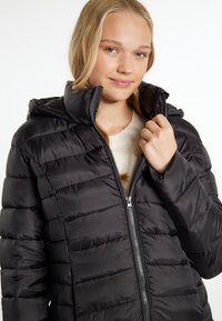 Abrigo puffer negro con capucha, que presenta segmentos acolchados y un cierre frontal. La tela tiene un acabado brillante, lo que proporciona una apariencia elegante.