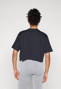 Black cropped t-shirt with a round neckline and short sleeves, paired with light grey leggings featuring textured details. Simple and fitted design.