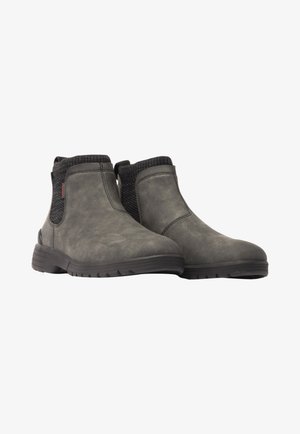 Botas de tobillo grises con una textura suave, paneles laterales elásticos y una suela de goma negra resistente, diseñadas para la comodidad y durabilidad.
