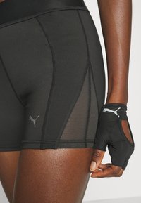 Pantalones cortos deportivos negros con paneles de malla y logo de Puma en gris, acompañados de guantes sin dedos negros con pequeños recortes y detalles del logo.