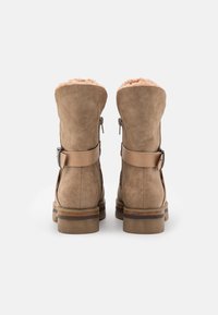 Ruske työnnysnilkkurit, joissa on turkiksen vuorelliset varret, sivuvetoketjut ja ruskea kerroksellinen lohkoillä, varustettuna hihnalla ja hopeisella soljella.