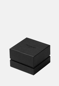 Svart texturerad rektangulär presentförpackning med slät yta, försedd med präglad märkning på locket, designad för elegant presentation.