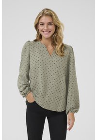 Lange mouw, olijfgroene blouse met een V-hals en zwarte stippen. De stof heeft een zachte textuur met gathered manchetten en een gebogen zoom.