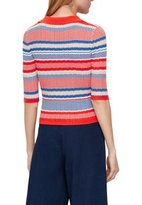 Rot, weiß und blau gestreifter Strickpullover mit kurzen Ärmeln und einem gerippten Kragen, der ein Zickzackmuster und ein kurzes Design aufweist.
