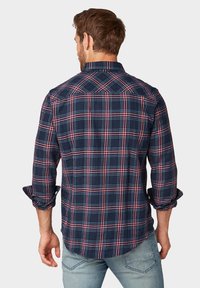 Camicia a quadri blu navy con motivi a scacchi rossi e bianchi, maniche lunghe, polsini con bottoni e una vestibilità casual. Materiale in cotone testurizzato.