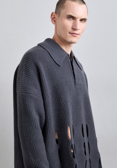 Pulover tricotat de culoare gri închis, cu guler, având un închidere cu fermoar și detalii decupate pe mâneci. Textură ribbed pe toată suprafața.