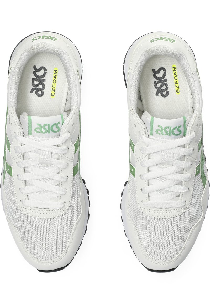 Zapatillas blancas con acentos verdes, materiales de malla y sintéticos, punta redondeada, cierre con cordones y suelas texturizadas. La vista superior muestra la marca.