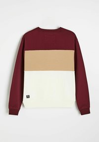 Bluza w kolorach bordowym, beżowym i kremowym, z poziomymi blokami kolorów oraz teksturowaną naszywką z tyłu. Zawiera metkę z logo.