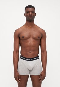 Graue Boxer-Shorts mit einem schwarzen elastischen Bund, auf dem der Text "JACK & JONES" zu sehen ist. Das Material wirkt weich und hat eine glatte Textur.