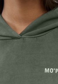 Sudadera con capucha verde con escote en V y material de algodón. Presenta texto blanco "MO’P" en el pecho. Textura suave y diseño casual.