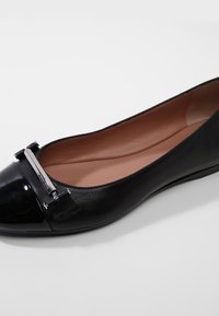 Czarne baletki z skóry naturalnej z lakierowanym noskiem i srebrnymi akcentami. Miękka wyściółka w jasnobeżowym kolorze.