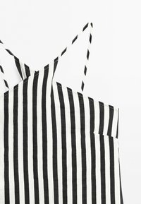 Black and white vertical striped sleeveless top with thin shoulder straps on a white background.