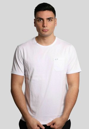 T-shirt bianca a maniche corte con scollo rotondo e taschino sul petto caratterizzato da un logo sottile. Tessuto liscio, vestibilità standard.
