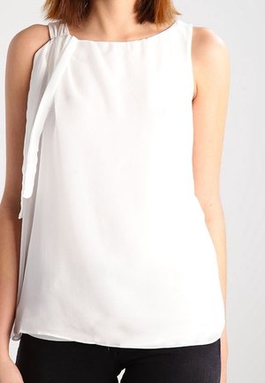 Blouse sans manches blanche en tissu léger, avec un col rond, des détails drapés verticaux et une coupe décontractée.